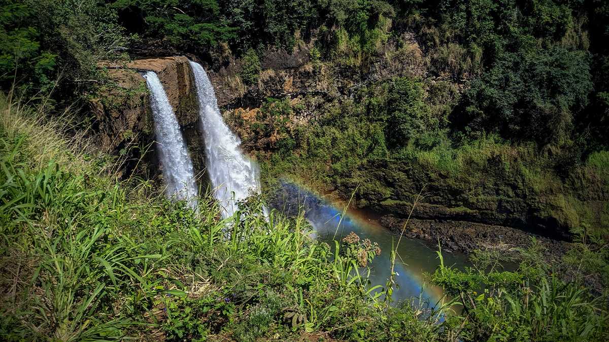 Aerial view of Wailua Falls with a small rainbow in Kauai, Hawaii, USA.